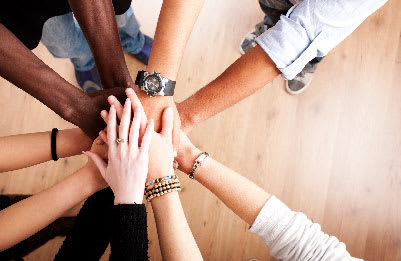 A graphic of a diverse work team putting their hands together for a team huddle representing effective communication