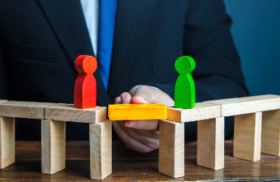 A graphic of a wooden bridge being built between two wooden peg people to symbolize conflict management