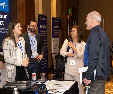 Leadership Summit attendees talking with an exhibitor at their booth
