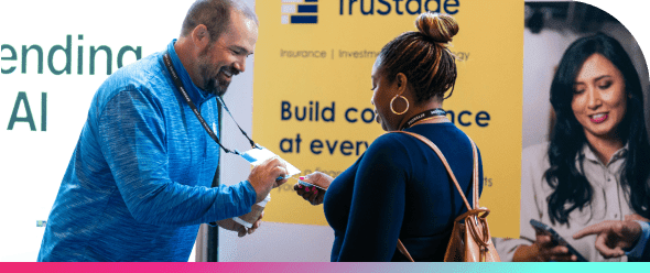 An attendee and sponsor exchange contact information at the Lending Tech Live exhibit hall