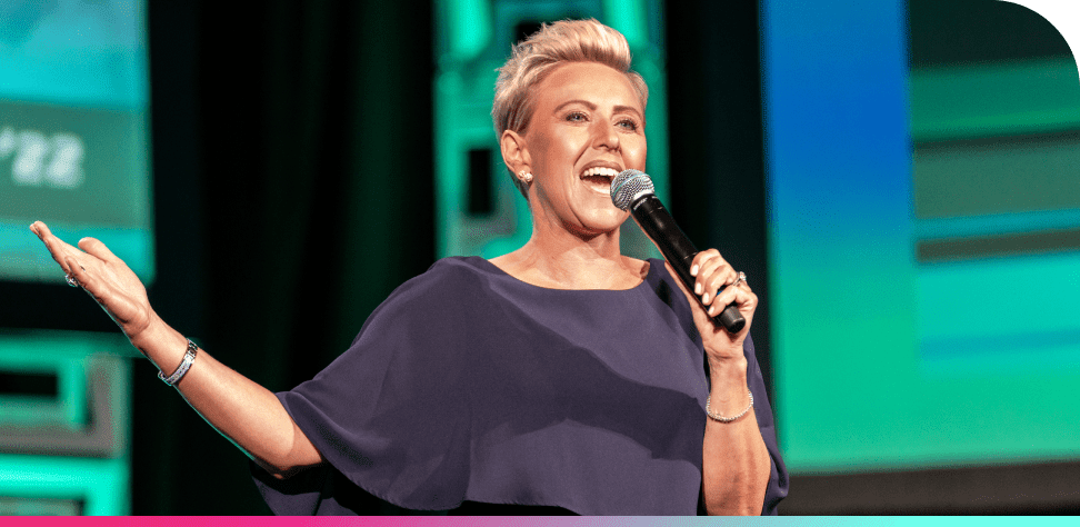 A female speaker holds a microphone on stage at Lending Tech Live