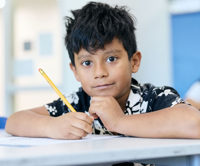 Student boy sitting at desk with pencil in hand